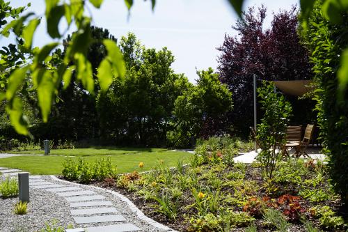 Jardin avec plusieurs revêtement et un cheminement qui sinue vers une pelouse